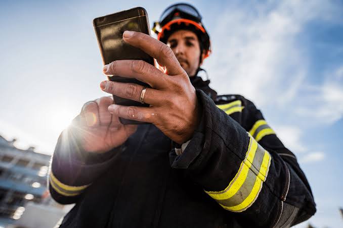 Un bombero utiliza su dispositivo móvil para comunicarse. Foto: Redes sociales referencial.